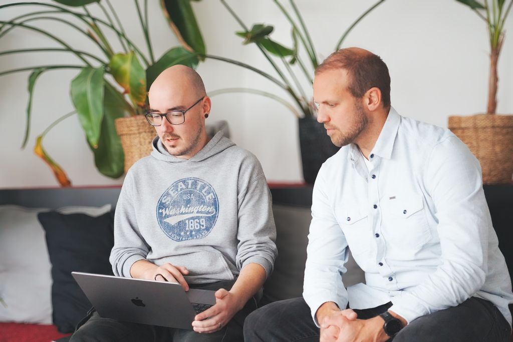 Zwei Männer arbeiten gemeinsam an einem Laptop.